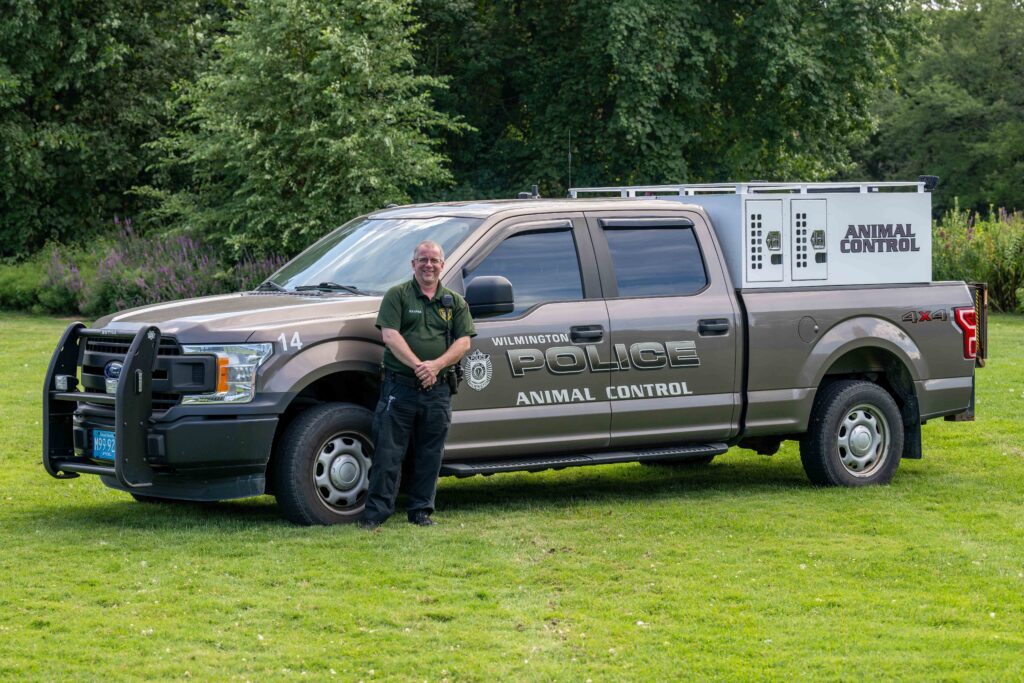 The animal control officer stands next to the ACO truck.